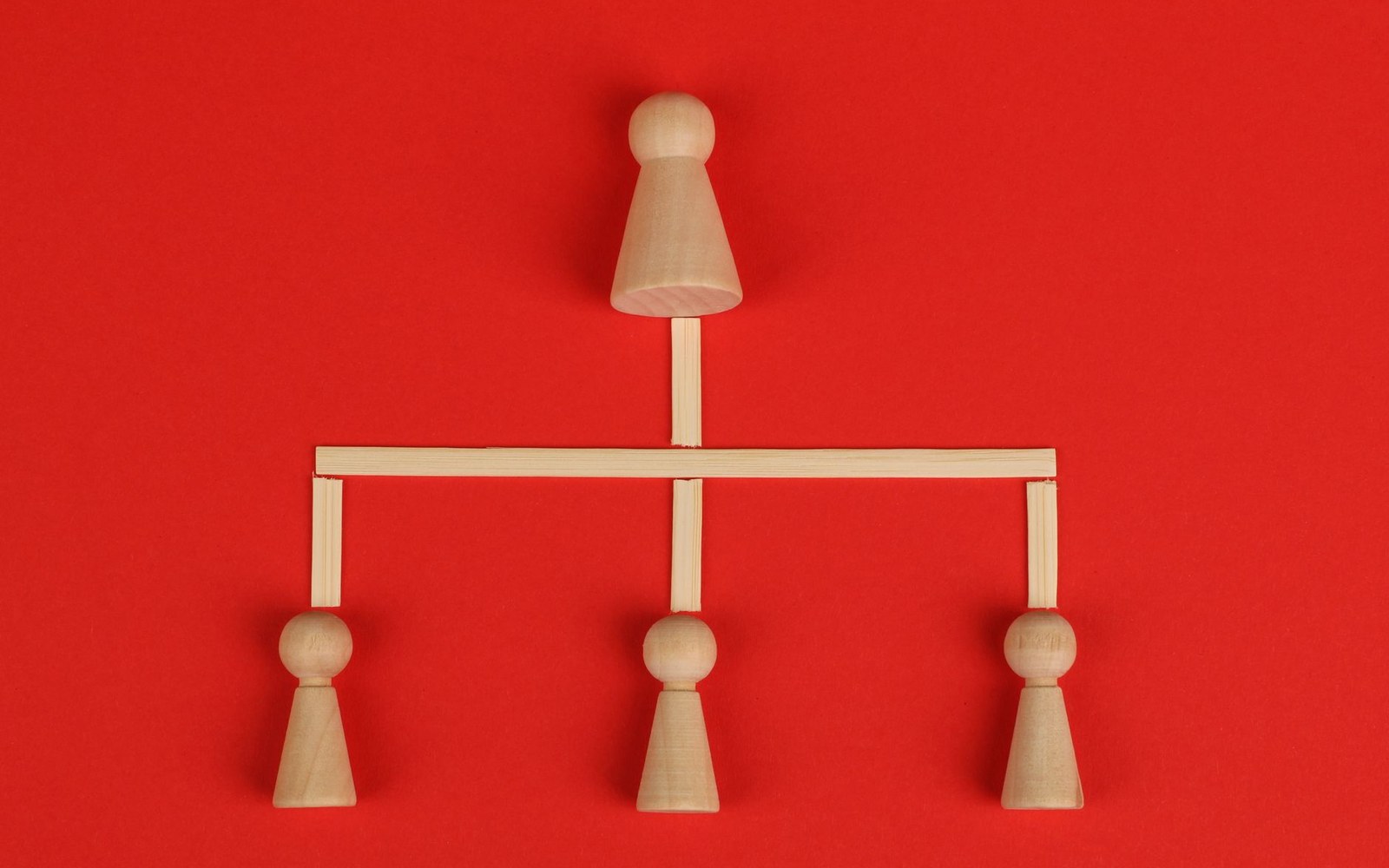 Wooden peg figures arranged in an organizational chart with sticks connecting one leader to three others