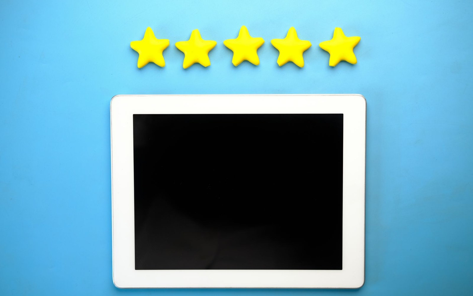 Five yellow star cutouts arranged above a blank tablet screen on a blue background