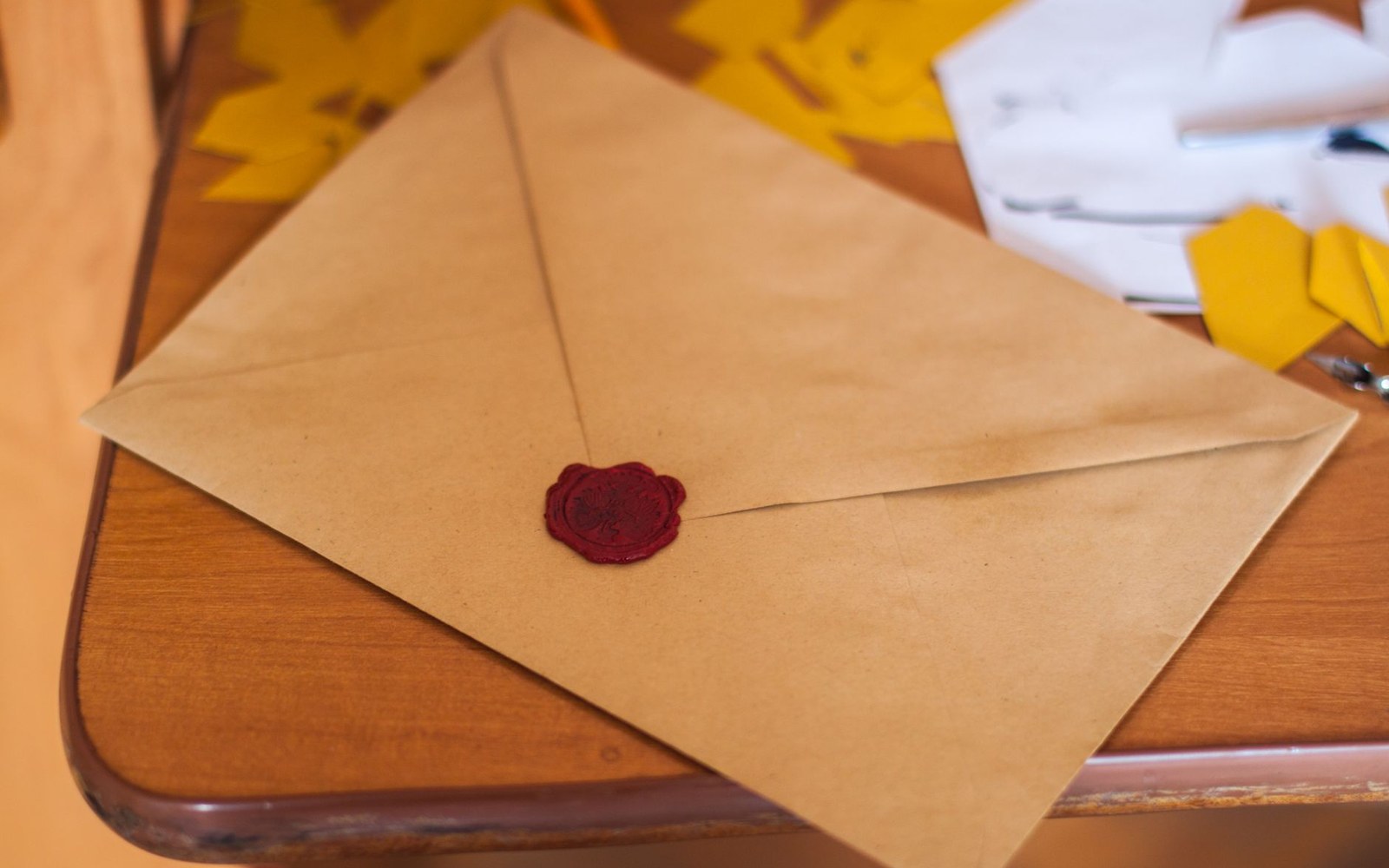 Kraft paper envelope sealed with a dark red wax stamp on a wooden desk