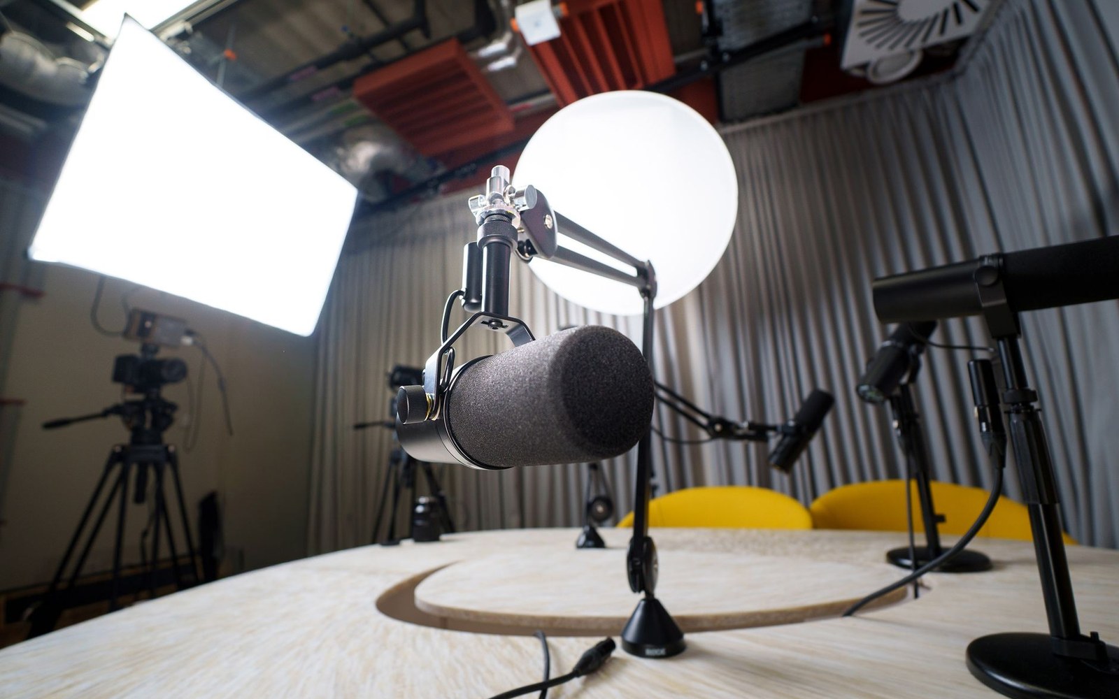 A studio microphone with pop filter set up on a table beside a softbox light